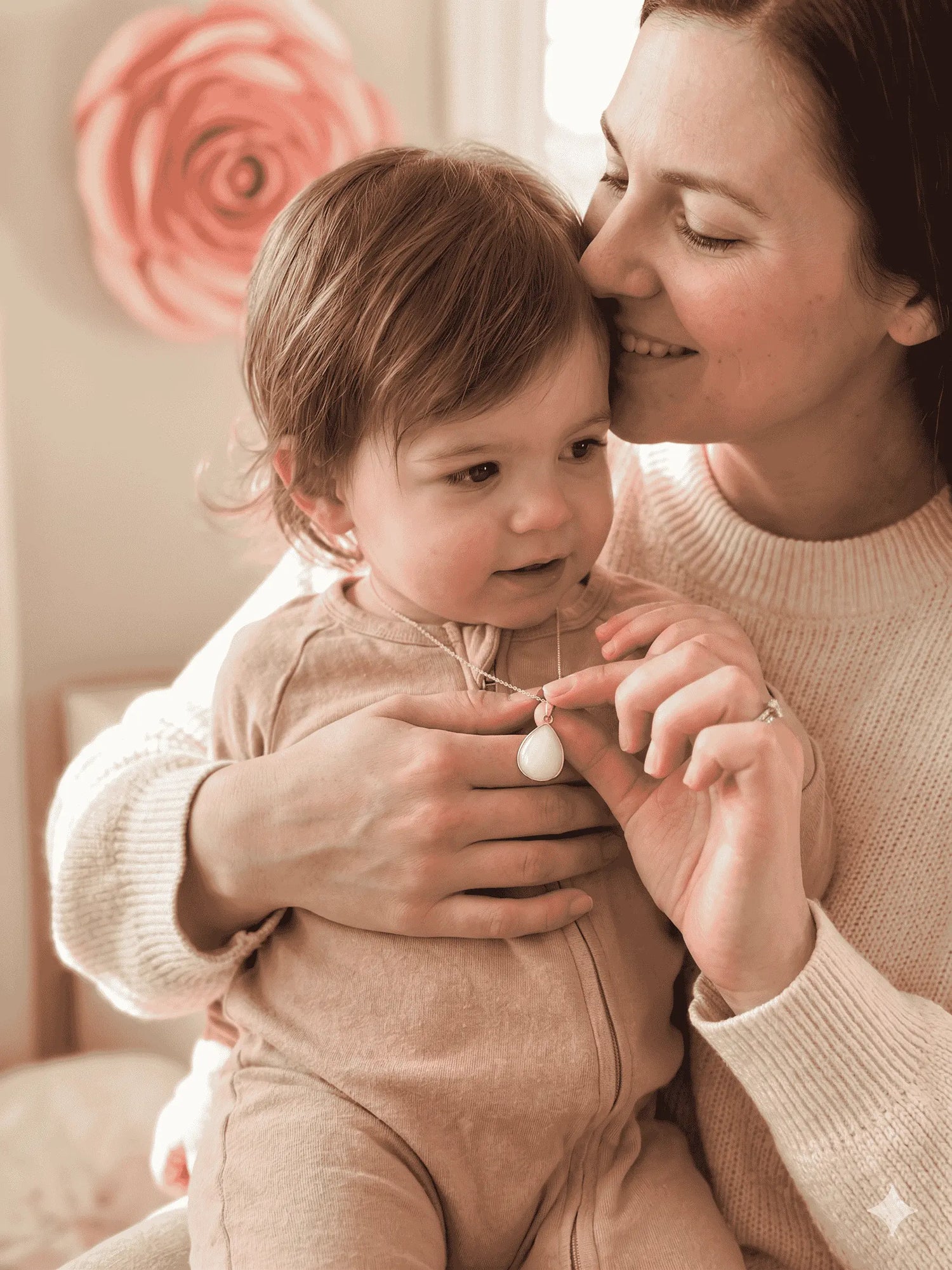Maman et bébé avec un collier pendentif en goutte, symbole de lien maternel et d'allaitement.